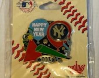 May include: A New York Yankees baseball pin with a blue, red, and white balloon that says "Happy New Year" and a party hat. The pin is on a white card with a baseball diamond pattern.