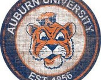 May include: A vintage-style circular wooden sign with a distressed blue and white background. The center features a cartoon orange tiger with a blue hat, and the text "Auburn University Est. 1856".