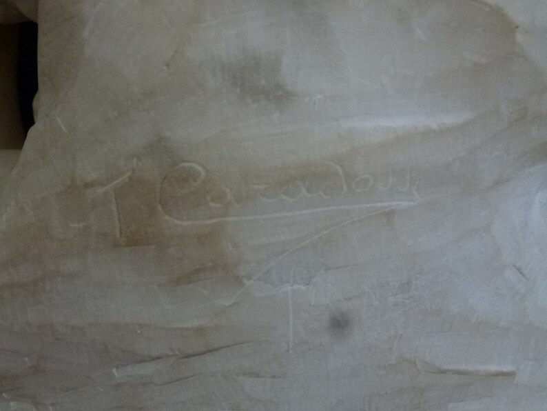 May include: Close-up of a white marble sculpture with the inscription "T. Cavazza" carved into the surface.