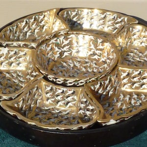 May include: A round, black serving tray with six white and gold bowls. The bowls have a pattern of white birds on a gold background.