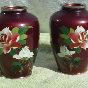 Peut inclure: Deux vases floraux rouge et blanc avec une bordure argentée. Les vases sont décorés de roses et de feuilles.