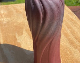 May include: A tall, burgundy-colored vase with a textured, swirling design. The vase has a wide opening and a hexagonal base. The color gradient transitions from a darker shade at the top to a lighter shade at the bottom. The vase is made of ceramic.
