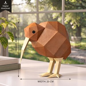 May include: A geometric kiwi bird sculpture made of brown and light yellow panels. The figure features a long, pointed beak, a round black eye, and angular body segments. It stands on two legs and measures 20 cm in height and 20 cm in width.