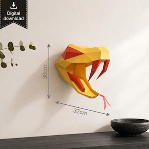 May include: A low-poly geometric snake head wall sculpture in yellow and red with a protruding tongue and fangs. The design features a digital download label and dimension markers indicating a height of 30cm and a width of 32cm on the wall.