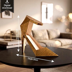 May include: A gold-colored geometric papercraft high-heeled shoe sculpture with a textured surface. The object features a height of 9.06 inches and a depth of 7.87 inches. A digital download icon is visible in the upper left corner of the image.