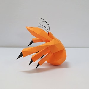 Puede incluir: Escultura de papel naranja de un cangrejo con garras y antenas negras.