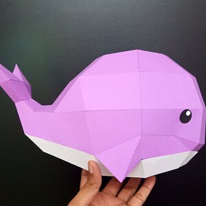 May include: A purple papercraft whale with a white belly. The whale is made of folded paper and has a 3D effect.