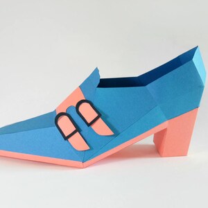 May include: A blue and pink papercraft shoe with a high heel and two black buckles.