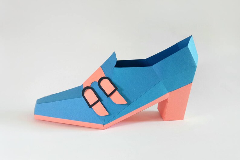 May include: A blue and pink papercraft shoe with a high heel and two black buckles.