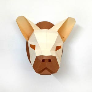 May include: A papercraft sculpture of a French bulldog head, with a white and brown colour scheme. The sculpture is made of folded paper and has a three-dimensional effect.