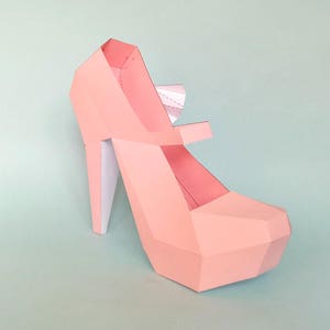 Puede incluir: Un zapato de tac&oacute;n alto de papel rosa con un dise&ntilde;o geom&eacute;trico.