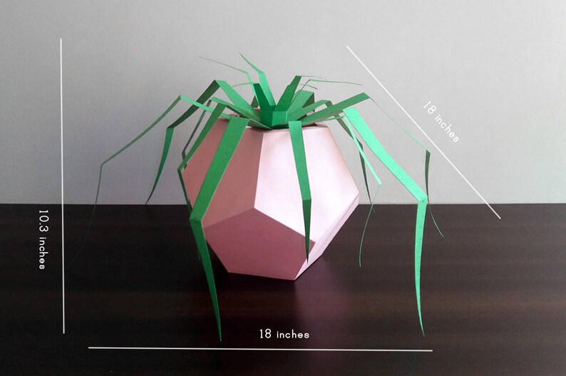 May include: A pink geometric paper vase with green paper leaves. The vase is 10.3 inches tall and 18 inches wide.