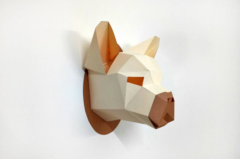 May include: A white papercraft animal head sculpture with brown accents. The sculpture is mounted on a brown circular base and appears to be a dog or wolf.