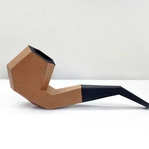 Peut inclure: Une pipe en carton marron avec un embout noir. La pipe est faite de carton pli&eacute; et a un design simple.