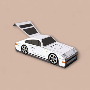 May include: A white sports car illustration with black accents, including wheels and window trim. The car has a detailed design, with a raised rear section. The background is a solid tan color.