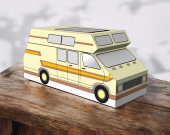Puede incluir: Maqueta de furgoneta camper amarilla y blanca con rayas marrones y naranjas. La furgoneta tiene forma rectangular con ventanas y una claraboya. El modelo está sobre una superficie de madera.