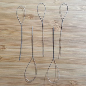 May include: Six silver-colored, thin, looped, wire tools for beading or jewelry making.