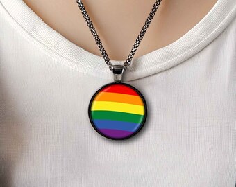 Puede incluir: Un collar de cadena plateada con un colgante redondo que presenta la bandera del arcoíris del orgullo.