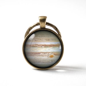 Könnte beinhalten: Ein Bronceanhänger mit einer Glaskuppel, die ein detailliertes Bild von Jupiter zeigt, dem größten Planeten unseres Sonnensystems. Das Bild zeigt die wirbelnden Wolken des Planeten und den Großen Roten Fleck.