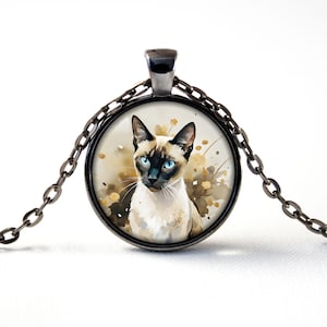 May include: A silver chain necklace with a round glass pendant featuring a watercolour painting of a Siamese cat with blue eyes.