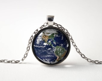May include: A silver chain necklace with a round glass pendant featuring a detailed image of the Earth. The pendant shows the continents and oceans in realistic colors.