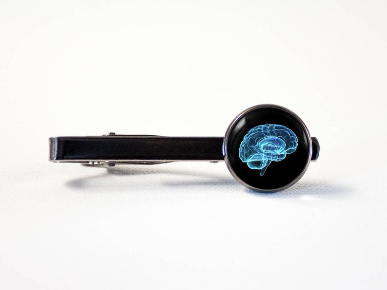 May include: A silver tie bar with a black background and a blue outline of a brain.