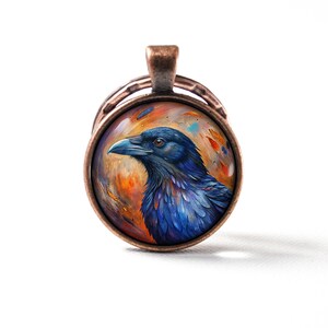 May include: A copper pendant with a round glass cabochon featuring a detailed painting of a blue raven with a black beak against a colourful background.