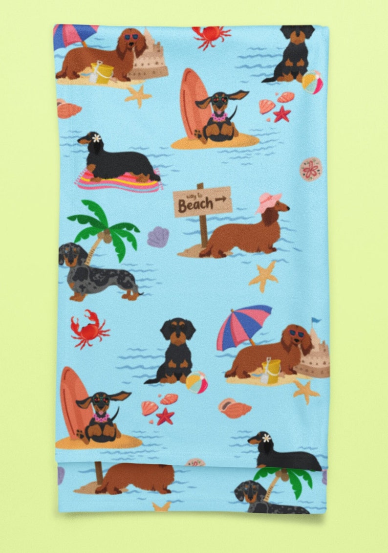 May include: A blue beach towel with a repeating pattern of dachshund dogs enjoying summer activities. The dogs are wearing sunglasses, hats, and leis. Some are surfing, others are relaxing under umbrellas, and some are building sandcastles. The text "Way to Beach" is on a sign.