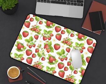 May include: A white mouse pad with a repeating pattern of red strawberries and green leaves. The mouse pad is on a black surface with a laptop, notebooks, and a cup of coffee.