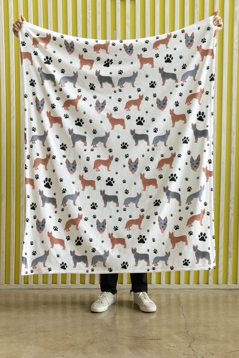 Peut inclure: Une couverture en polaire blanche avec un motif r&eacute;p&eacute;t&eacute; de chiens bergers australiens bleus et bruns et d'empreintes de pattes noires.