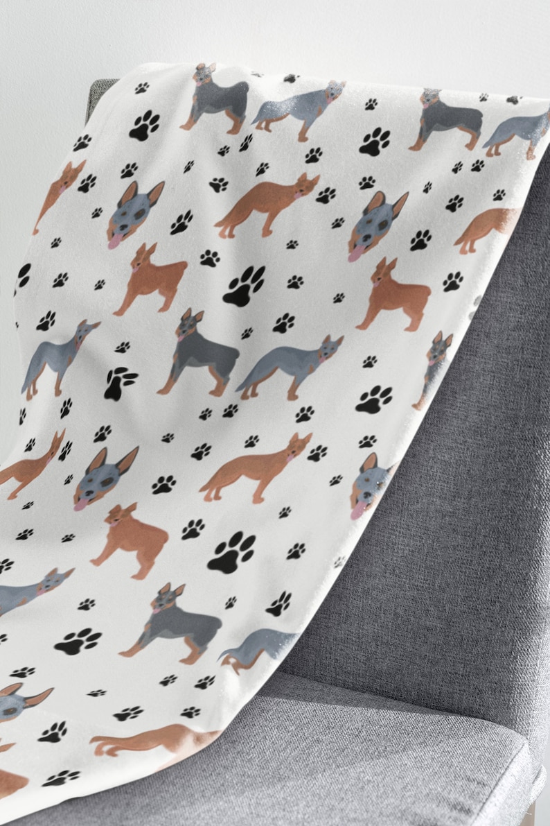 Peut inclure: Une couverture en polaire blanche avec un motif r&eacute;p&eacute;t&eacute; de chiens bergers australiens bleus et bruns et d'empreintes de pattes noires.