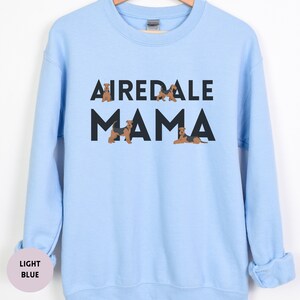 May include: A light blue sweatshirt with the text "Airedale Mama" in black letters. There are small images of Airedale Terriers around the text.