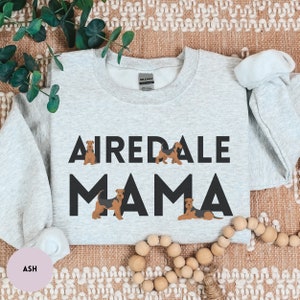 May include: A gray sweatshirt with the text "Airedale Mama" in black letters. The text is surrounded by four small illustrations of Airedale Terriers.