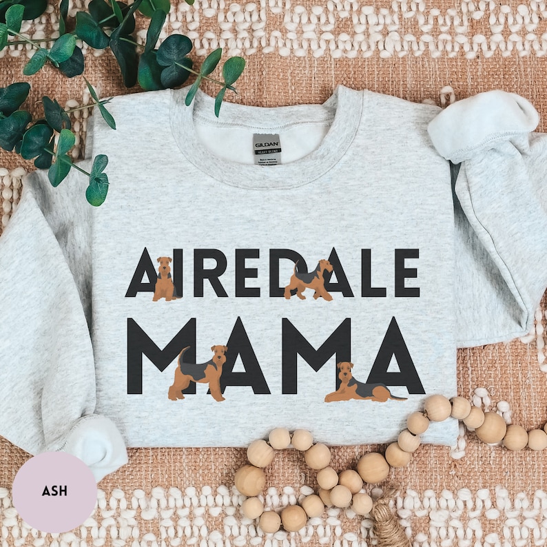 May include: A gray sweatshirt with the text "Airedale Mama" in black letters. The text is surrounded by four small illustrations of Airedale Terriers.