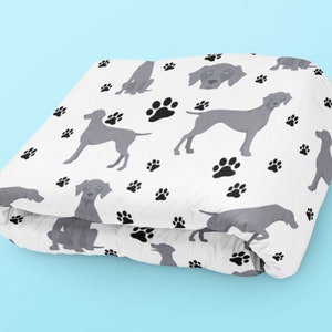 May include: White fabric with a repeating pattern of grey Weimaraner dogs and black paw prints.