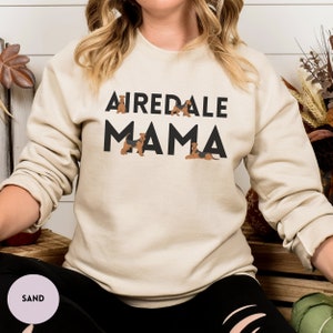 May include: A beige sweatshirt with the text "Airedale Mama" in black letters. The text is surrounded by small images of Airedale Terriers.