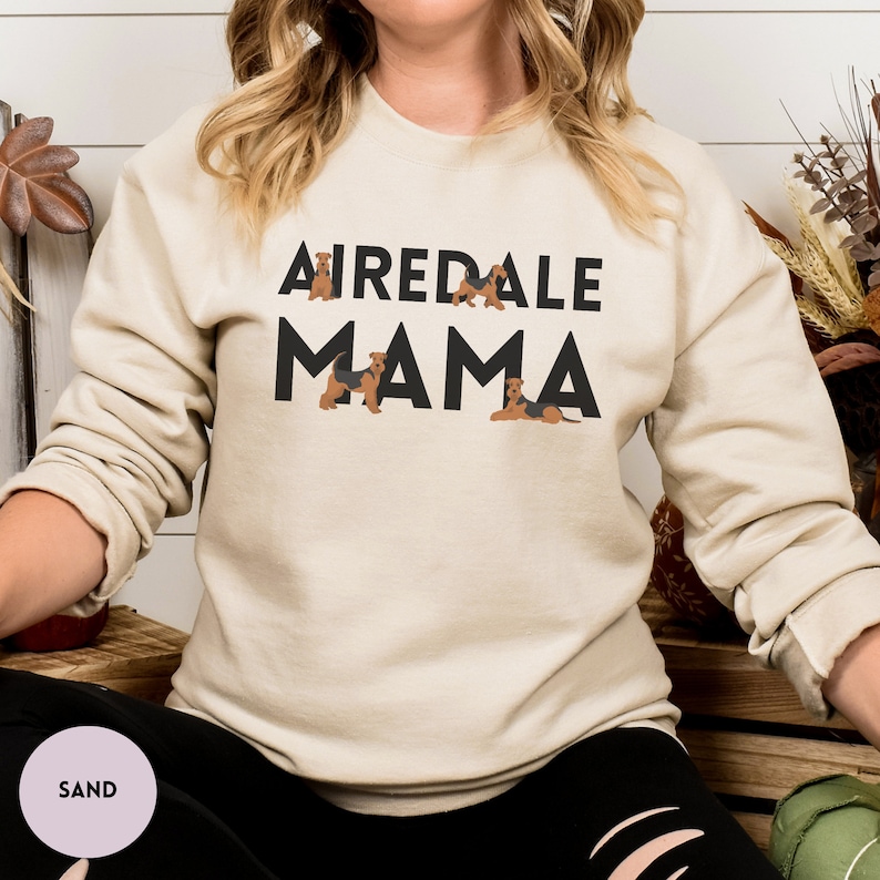May include: A beige sweatshirt with the text "Airedale Mama" in black letters. The text is surrounded by small images of Airedale Terriers.