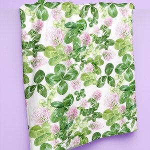 May include: White fabric with a repeating pattern of green clover leaves and pink clover flowers.