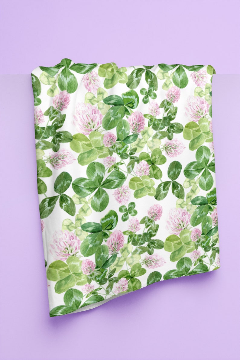 May include: White fabric with a repeating pattern of green clover leaves and pink clover flowers.