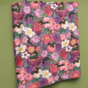 May include: A purple fabric with a floral pattern featuring black and brown dachshunds sleeping in the flowers. The flowers are pink, red, white, and yellow.