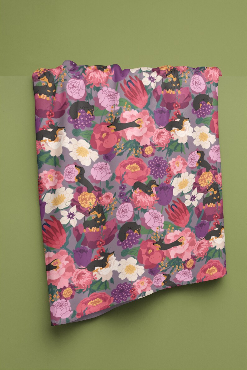 May include: A purple fabric with a floral pattern featuring black and brown dachshunds sleeping in the flowers. The flowers are pink, red, white, and yellow.