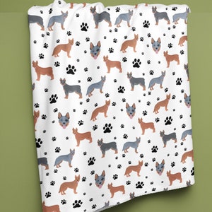 Peut inclure: Tissu blanc avec un motif r&eacute;p&eacute;t&eacute; de chiens bergers australiens bleus et bruns et d'empreintes de pattes noires.
