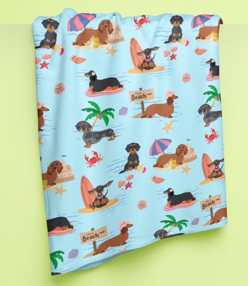 May include: A blue and white beach themed fabric with a repeating pattern of dachshunds wearing sunglasses, hats, and holding surfboards. The text "Way to Beach" is repeated on the fabric.