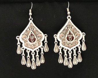 Puede incluir: Un par de pendientes de plata con un diseño de esmalte rosa y rojo. Los pendientes tienen forma de lágrima con un patrón de filigrana y múltiples colgantes de lágrima.