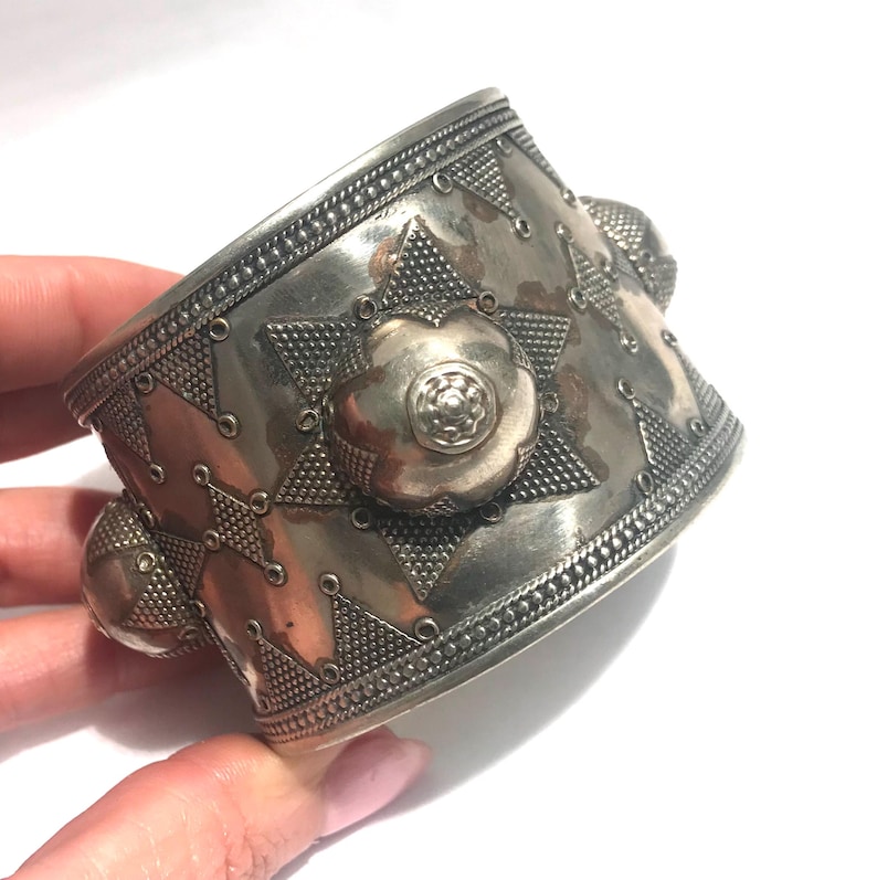 Op de afbeelding: Een zilveren armband met een geometrisch ontwerp en drie verhoogde cirkels. De armband is gemaakt van metaal en heeft een glanzende afwerking.