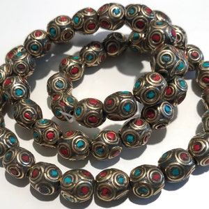 May include: A strand of oval-shaped beads with a gold finish. The beads are decorated with turquoise and red accents.