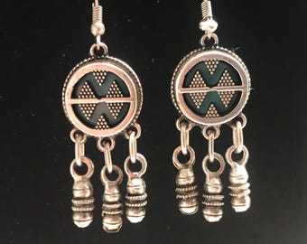 May include: Silver dangle earrings with a round, black and green patterned charm and three silver beads hanging from each charm.