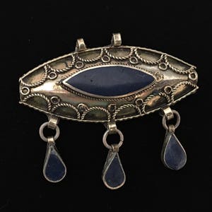 May include: A silver pendant with a blue stone in the center and three blue stone drops hanging from the bottom.