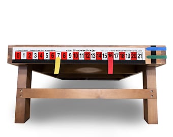 May include: A wooden cornhole game with a black and white score strip featuring red numbers from 0 to 21. The score strip has yellow, red, and blue tabs. The game is on a wooden stand.