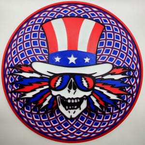 May include: A circular, red, white, and blue graphic featuring a skull wearing sunglasses and an Uncle Sam hat. The design includes a blue and white diamond pattern border and red, white, and blue accents, creating a patriotic theme.